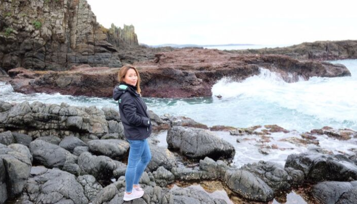 CDU student Pattarawadee Chatleelawat stands on rocks at the water's edge
