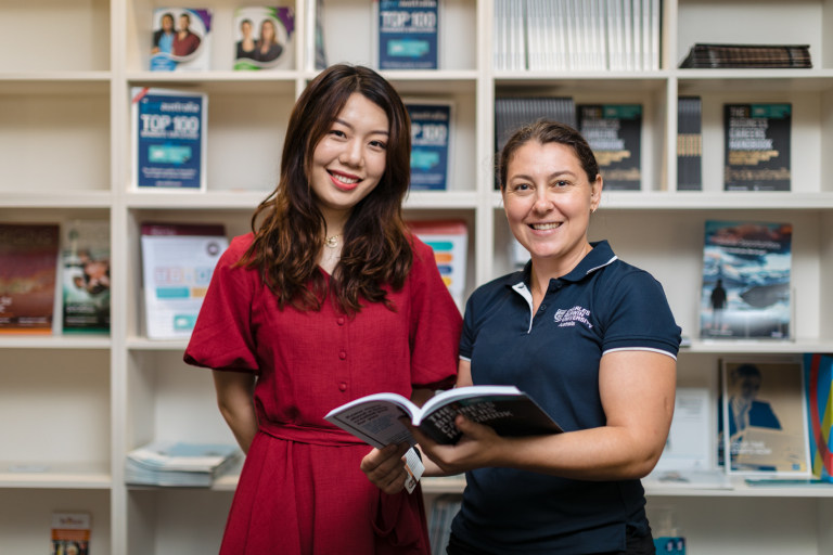 CDU student Sunny looking through a document with a CDU staff member