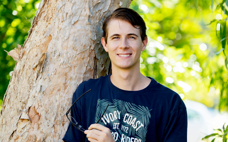 CDU student Drew Whitehouse smiling at the camera surrounded by trees
