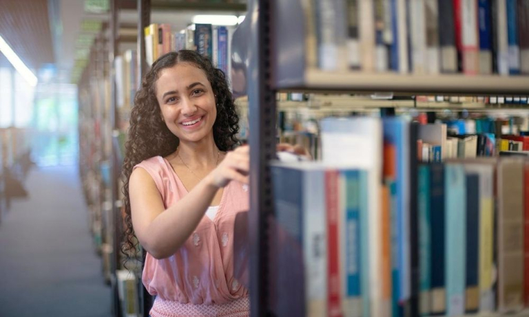 CDU student Nancy Soliman in the library choosing a book.