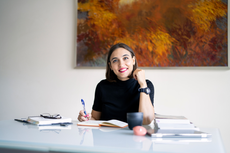 Yuliia Shchedrovska writing at a desk / working from home