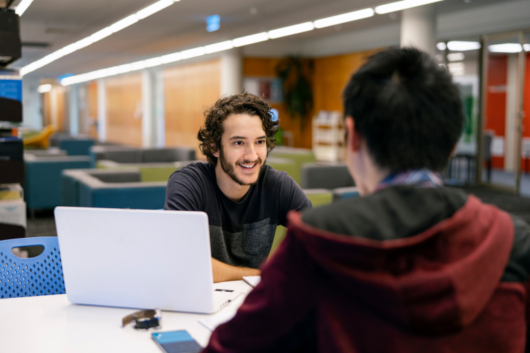 CDU student Nicholas in the library with a study buddy
