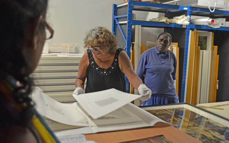 Karen Rogers (Ngukurr Arts) and Rose Wilfred (Numbulwar Numburindi Arts) examine prints at CDU Art Collection and Gallery