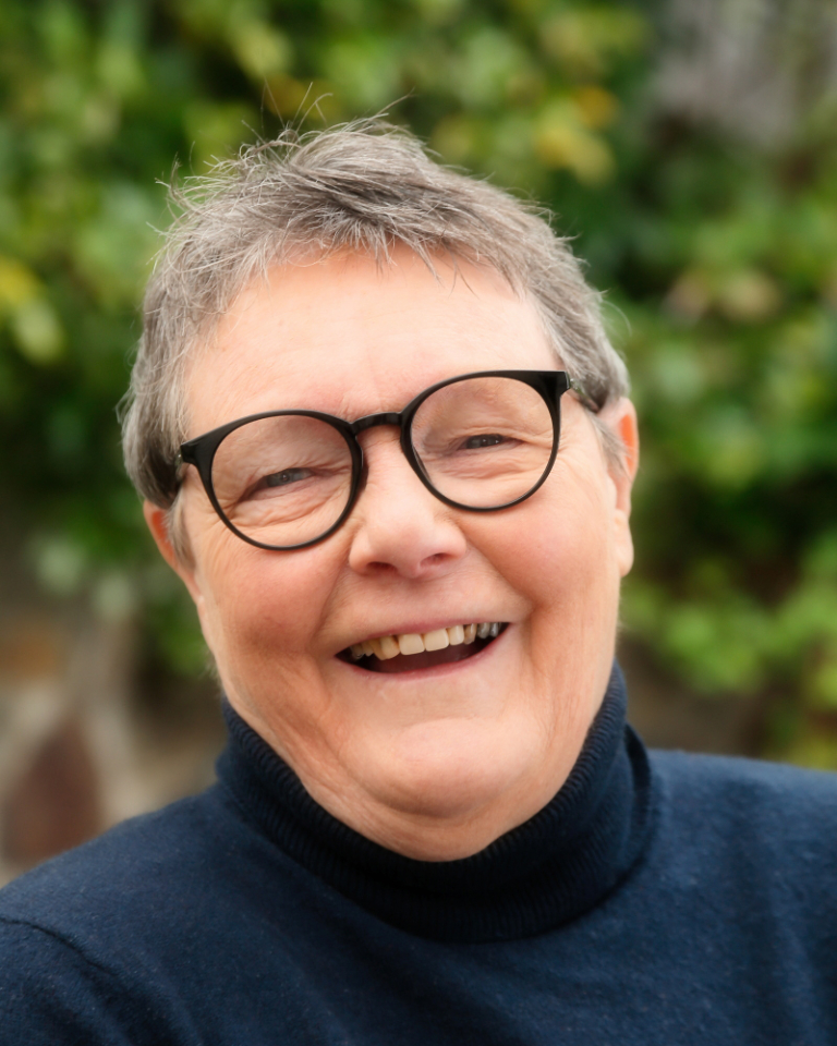 Professor Helen Verran Smiling in front of green trees