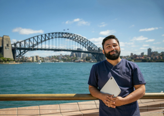 CDU nursing student in front of the Sydney Harbour Bridge holding a laptop
