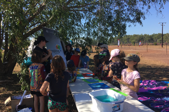 children and Carla standing around table under tree