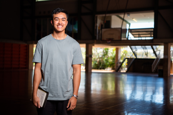 Student standing in gym holding notepad