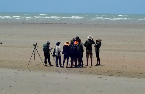 a group of people on a beach with the ocean in the distance