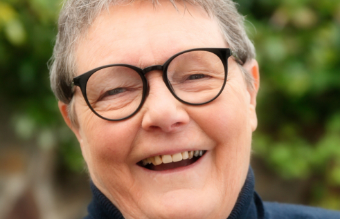 Professor Helen Verran Smiling in front of green trees