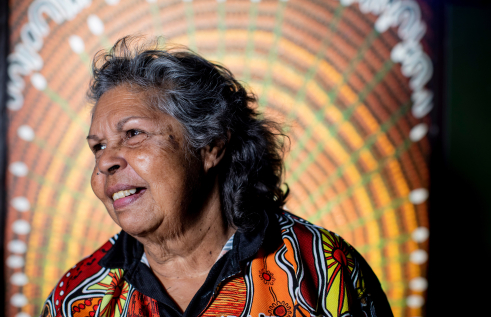 First Nations women smiling in front of Indigenous Art