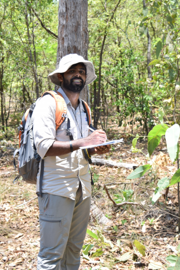 Man standing in forest writing in a notebook